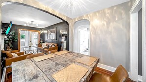 Un salon spacieux avec une grande table à manger en bois, des sièges confortables et une vue sur la cuisine adjacente.