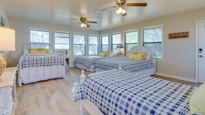Ein Schlafzimmer mit drei Betten, großen Fenstern, Deckenventilatoren und einem Schild mit der Aufschrift 'LAKE'.