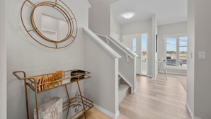 Een modern interieur met een trap, een wandspiegel en een metalen trolley met boeken.