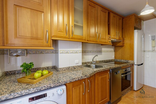 Una cocina con armarios de madera, encimera de granito, lavavajillas integrado y horno de acero inoxidable.