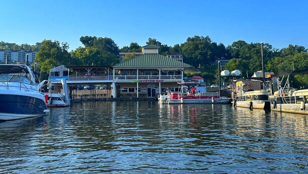 Un port de plaisance avec des bateaux amarrés, un restaurant situé au bord de l’eau et un bâtiment doté d’un toit végétalisé.