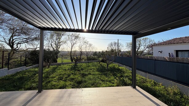 A covered outdoor area with a view of a garden and a building in the background. - Villa Climatisée Proche Centre (Uzès)