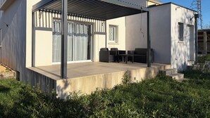 A modern house with a covered patio, large sliding glass doors, and outdoor seating. - Villa Climatisée Proche Centre (Uzès)