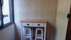 Ein Eckzimmer mit einem weißen Schreibtisch, zwei Schubladen und einem hölzernen Hocker.