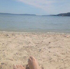 A sandy beach with a clear view of the sea and distant hills.