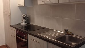 Eine moderne Küche mit hellen Holzschränken, einer schwarzen Arbeitsplatte, einem eingebauten Ofen und einer Edelstahlspüle.