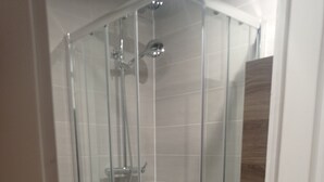 Eine Duschkabine aus Glas mit direkt angrenzender Toilette.