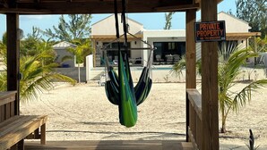 A wooden deck with a hammock hanging, a sign reading "FOXTAIL PALM VILLA", and a "PRIVATE PROPERTY NO TRESPASSING" sign. - BRAND NEW Beachfront Villa best sandy beach in TCI with pool Fox Tail Palm Villa (Whitby)