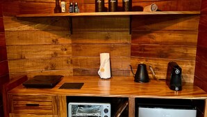 A compact kitchen with wooden cabinetry, a built-in toaster, a coffee maker, and a small refrigerator. - Naturave #1 Into the woods, 1 (Monte Verde)