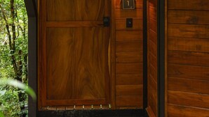 A wooden door with a small window, a number plaque, and a doorbell. - Naturave #1 Into the woods, 1 (Monte Verde)