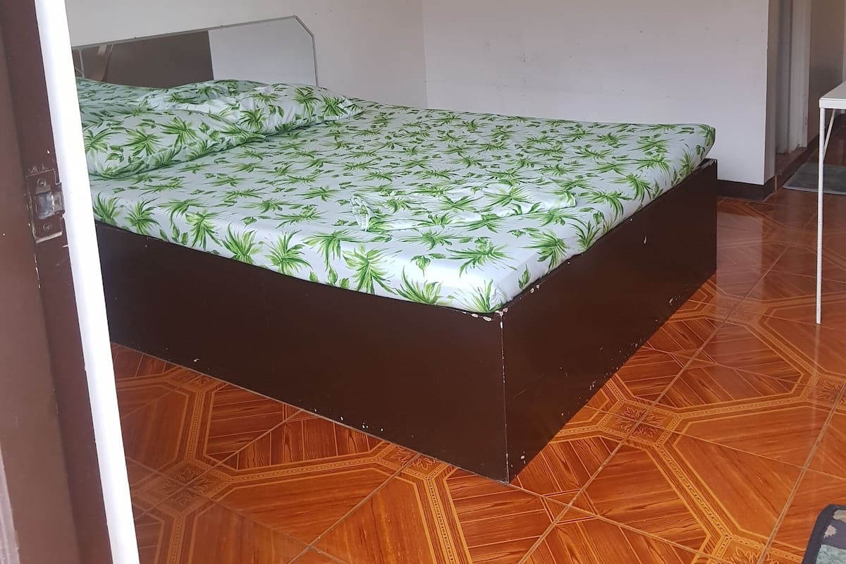 Une pièce avec un lit, une chaise et un sol à motifs.