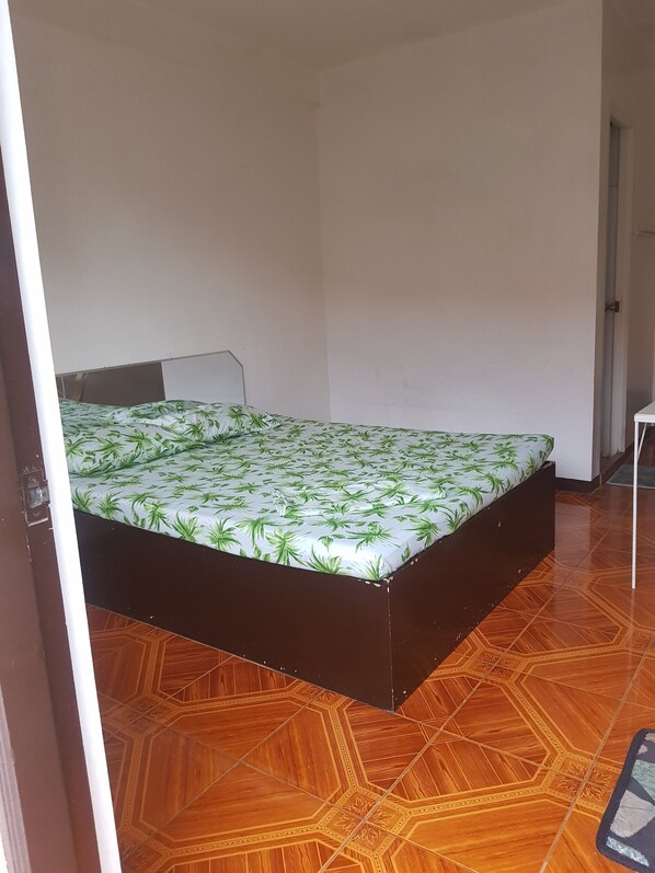 Una habitación con una cama, una silla y un piso estampado.