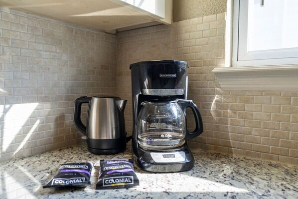 Une cuisine équipée d’une machine à café, d’une bouilloire et de deux paquets de café.