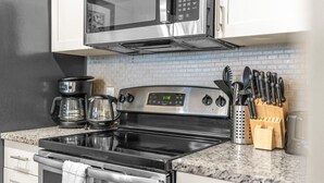 A kitchen with a stainless steel stove, a coffee maker, and a microwave above it. - Your VIP Home near Disney! (Osceola County)