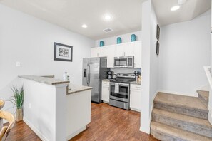 A modern kitchen with white cabinets, stainless steel appliances, and a granite countertop.