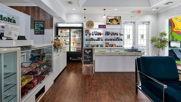 A cafe interior with a counter, refrigerated display, and seating area. - Your VIP Home near Disney! (Osceola County)