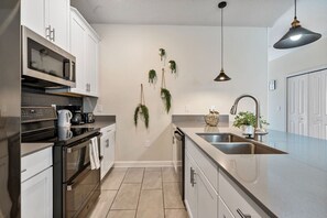Uma cozinha moderna com eletrodomésticos de aço inoxidável, uma ilha grande com pia e plantas decorativas.