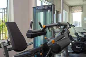 Uma academia com equipamentos de ginástica, incluindo um banco e uma máquina de musculação.