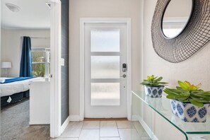 A hotel room with a bed, a window with curtains, a door with frosted glass panels, and a wall-mounted mirror. - Outstanding 5BDR Disney Vacation (Kissimmee)