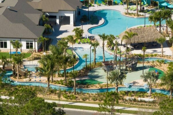A resort with multiple swimming pools, palm trees, and a thatched-roof structure. - Outstanding 5BDR Disney Vacation (Kissimmee)