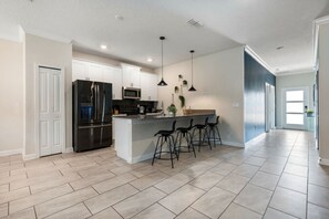 A modern kitchen with a central island, bar stools, and a refrigerator. - Outstanding 5BDR Disney Vacation (Kissimmee)
