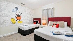A hotel room with two beds, a Mickey Mouse mural, and a red headboard. - Outstanding 5BDR Disney Vacation (Kissimmee)