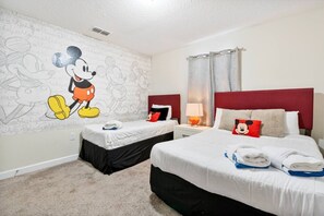A hotel room with two beds, a Mickey Mouse mural, and a red headboard. - Outstanding 5BDR Disney Vacation (Kissimmee)