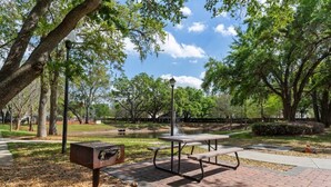 Un parque con mesas de picnic, una parrilla y un estanque.