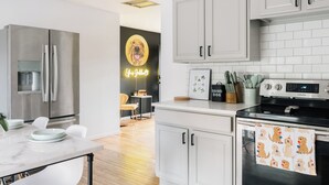 Una cocina moderna con armarios blancos, electrodomésticos de acero inoxidable y un letrero de neón.