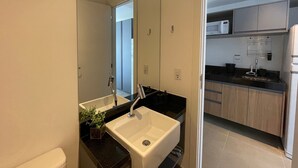 A modern bathroom with a white sink, a mirror, and a small plant. - Studio On Imarés Moema (São Paulo)