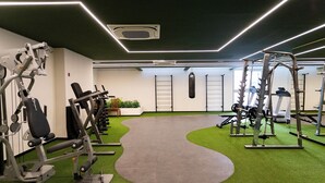 A gym with various exercise machines, a green artificial turf floor, and a grey padded area. - Studio On Imarés Moema (São Paulo)