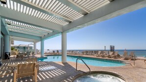 Área de piscina coberta ao ar livre com espreguiçadeiras e hidromassagem, com vista para o oceano.