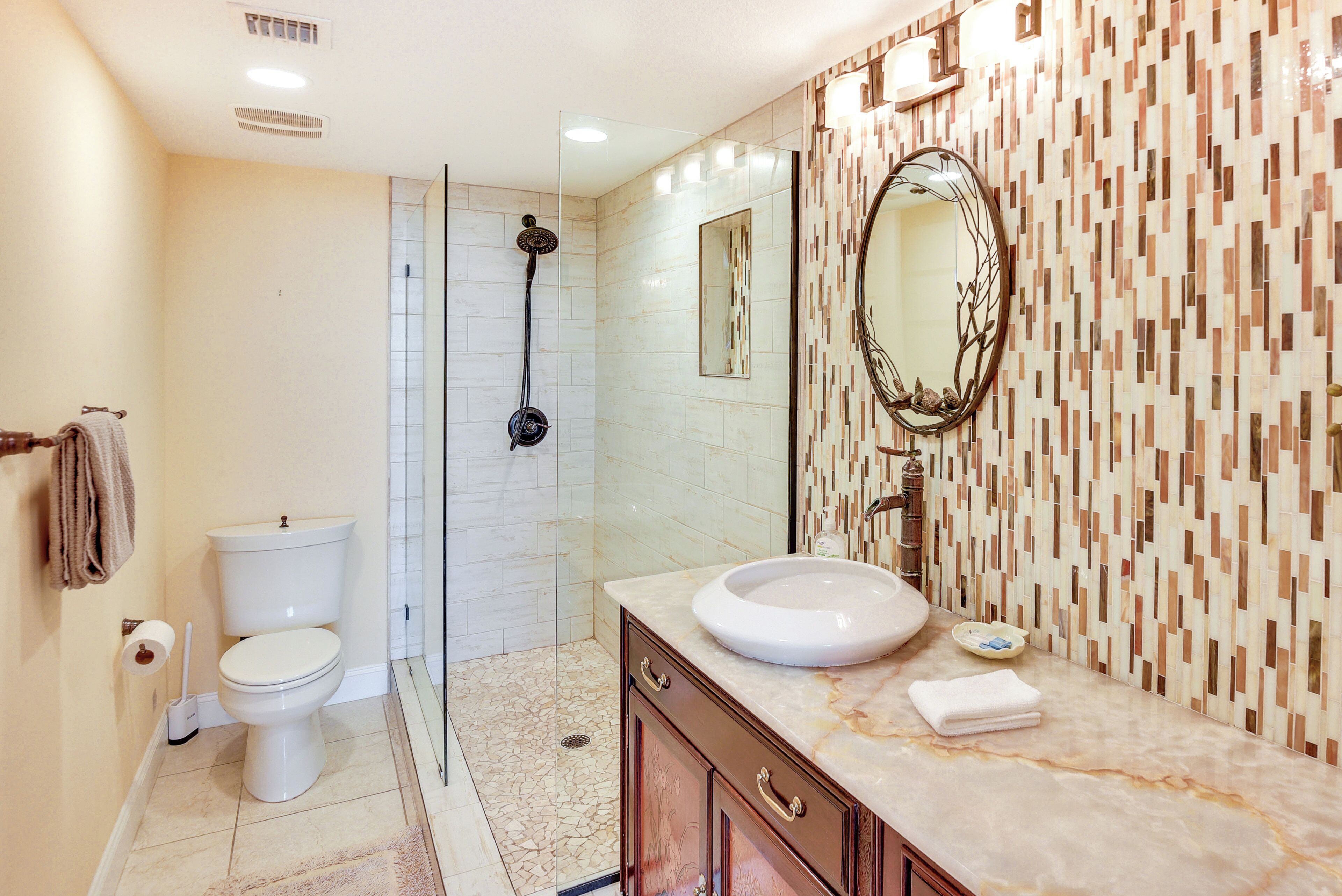 A bathroom with a toilet, a sink, a shower, and a mirror.