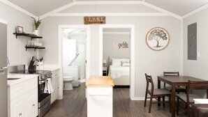 A compact kitchen with white cabinetry, a wooden countertop, and a built-in oven. A small wooden table and two chairs are positioned in the dining area.