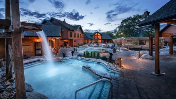Un complexe hôtelier doté d’un jacuzzi, de chalets en bois et d’une cascade.