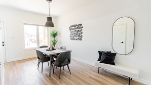 Un comedor moderno con una mesa de madera, sillas, una lámpara colgante y un espejo en la pared.