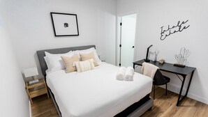 Un dormitorio ordenado con cama, mesita de noche y escritorio con silla.