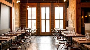A restaurant with brick walls, large windows, wooden tables, and hanging light fixtures. - Riverview Health | Trendy Area | Free Parking (Winnipeg)