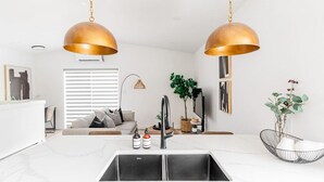 A modern kitchen with a central island, stainless steel sink, and pendant lighting. - Riverview Health | Trendy Area | Free Parking (Winnipeg)