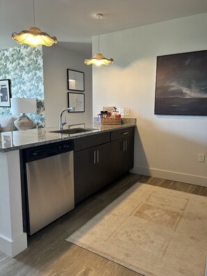 Enjoy cooking in this well-equipped kitchen with a dishwasher, dark cabinetry, and granite countertop.