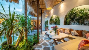 Un espace extérieur aménagé dans un style tropical, avec un sol en pierre, une piscine et une végétation luxuriante.