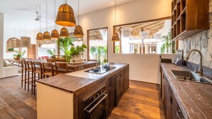 Une cuisine moderne avec des meubles en bois, un îlot central doté d’une cuisinière et des luminaires suspendus.