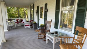 A covered porch with wicker furniture, a glass table, and green shutters. - Happy Moo's Fink Family Farm, where cows & guests are free to enjoy our 50 acres (Versailles)