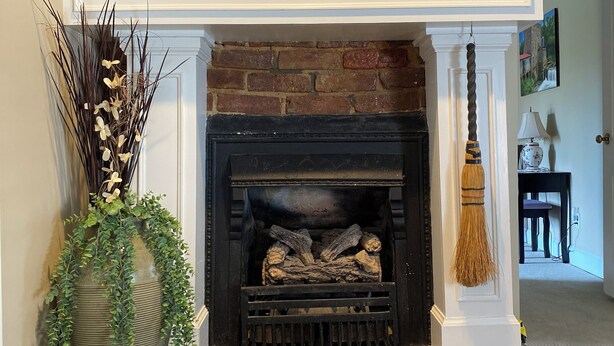 A fireplace with a brick surround, a large vase with greenery, and two lamps on either side. - Happy Moo's Fink Family Farm, where cows & guests are free to enjoy our 50 acres (Versailles)