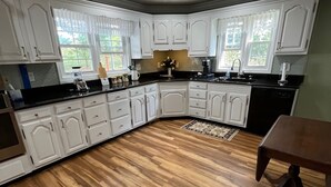 A modern kitchen with white cabinetry, a black countertop, and a wooden floor. - Happy Moo's Fink Family Farm, where cows & guests are free to enjoy our 50 acres (Versailles)