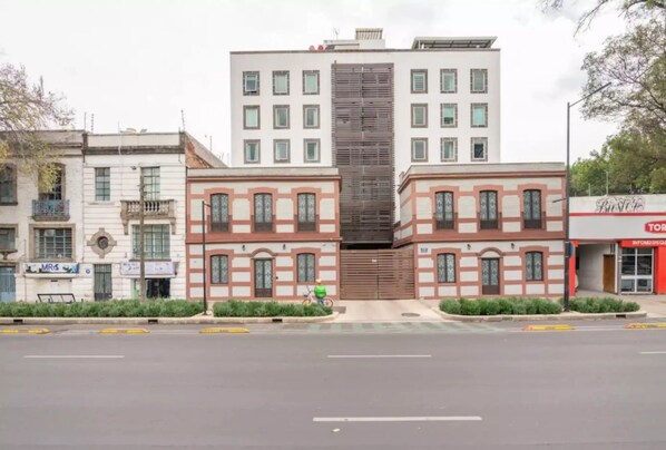 Un edificio de varios pisos con una sección vertical central y acceso al nivel de la calle.