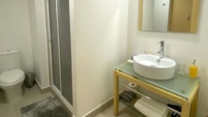 A modern bathroom with a toilet, sink, and shower.