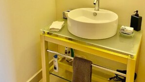 A bathroom with a round sink, a mirror, and a yellow vanity.