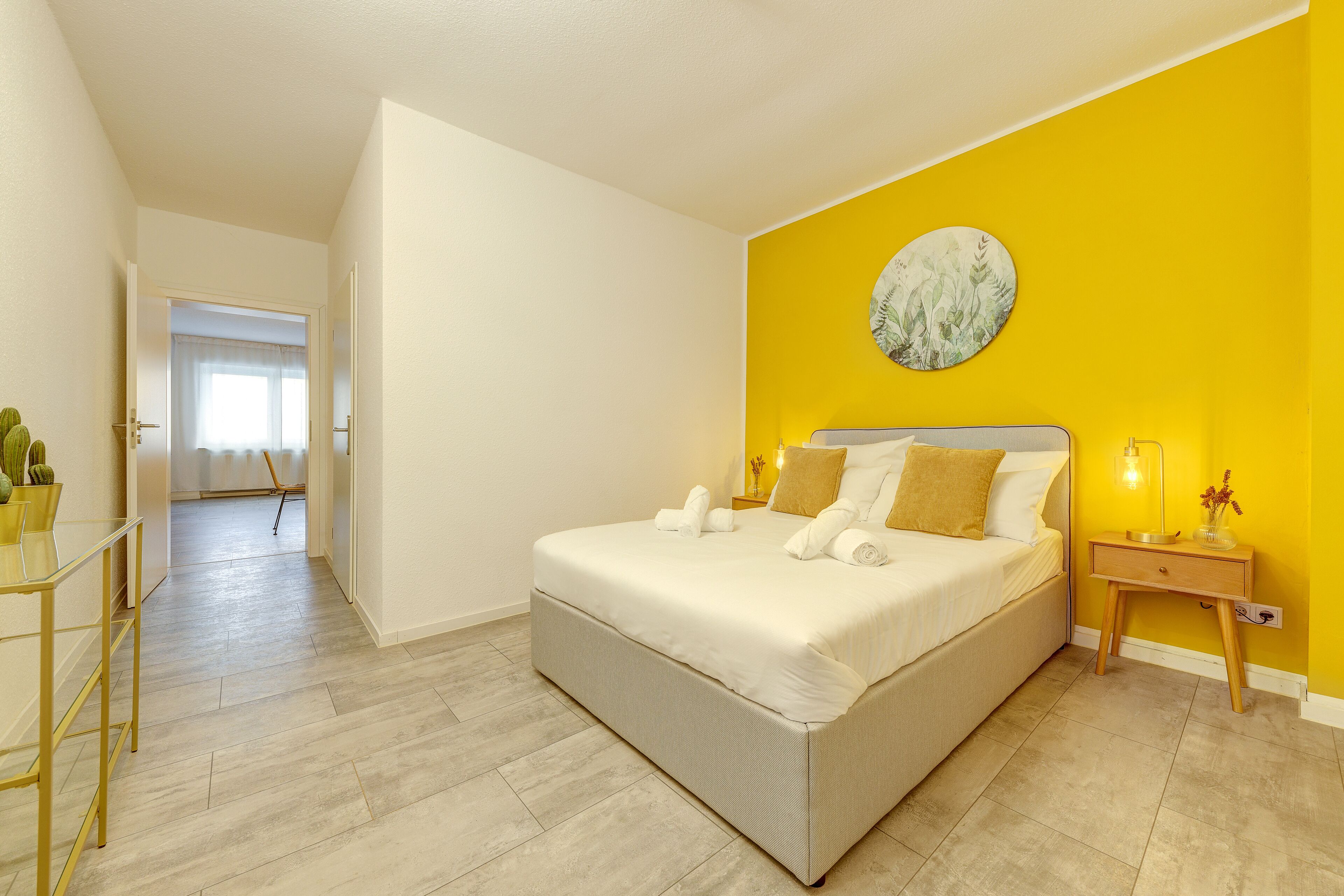 A bedroom with a bed, bedside table, and a wall with a circular artwork.