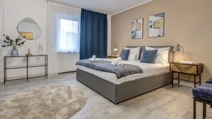 Un dormitorio moderno con una cama grande, mesitas de noche, un espejo y obras de arte en las paredes.